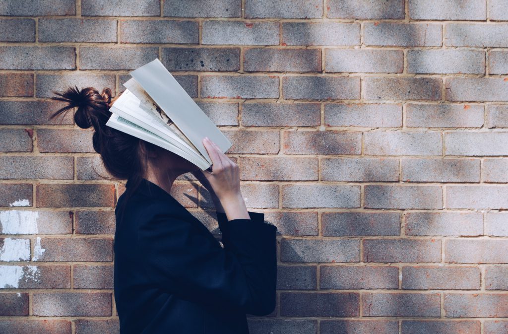 a person covering her face with a book