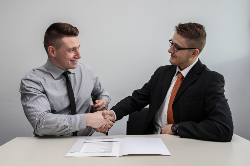 Two gentlemen shaking hands and smiling