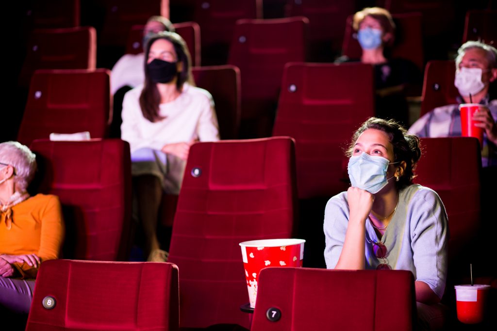 people wearing masks and watching movie in the theatre