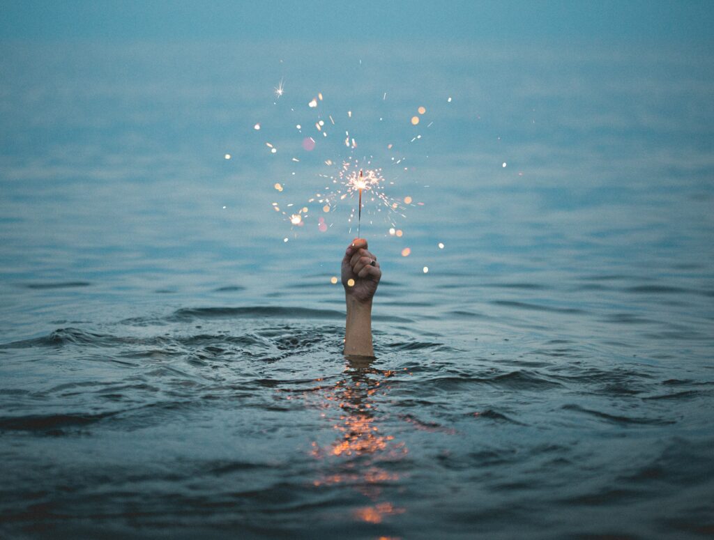 A hand holding a sparkler in a lake