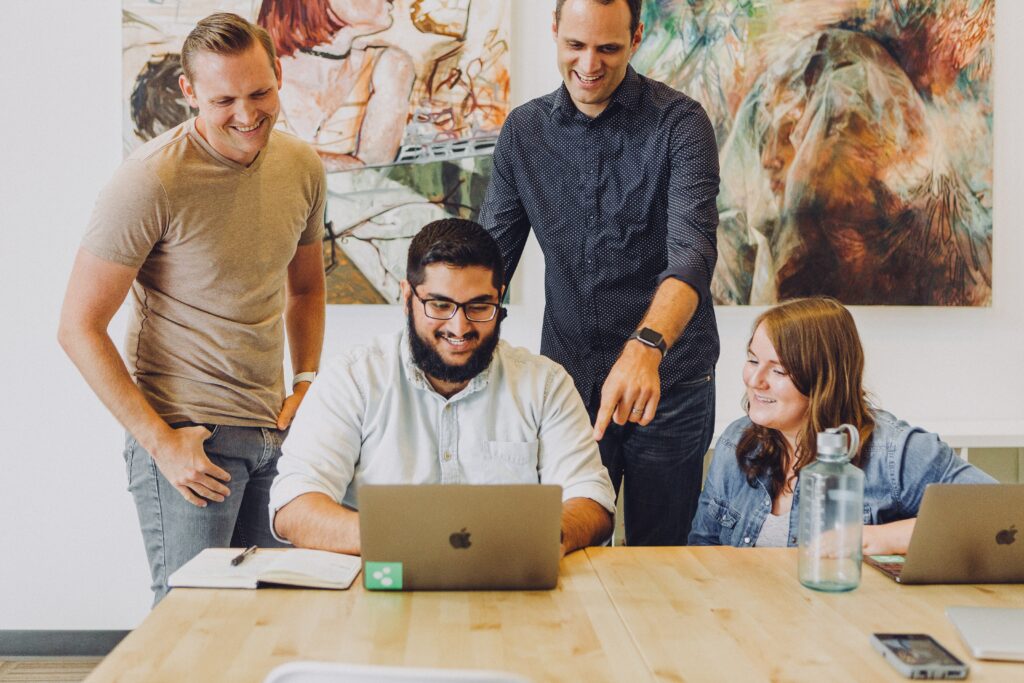 A group of employees gather around a laptop