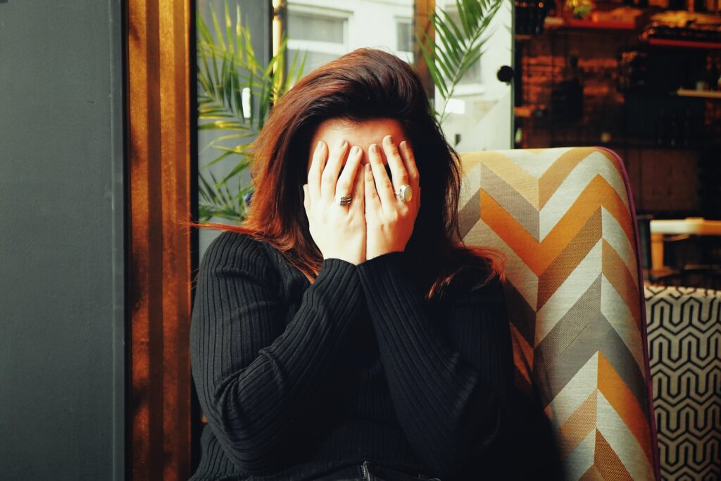 Woman covering her face owing to the fear and stress of her negative self-beliefs