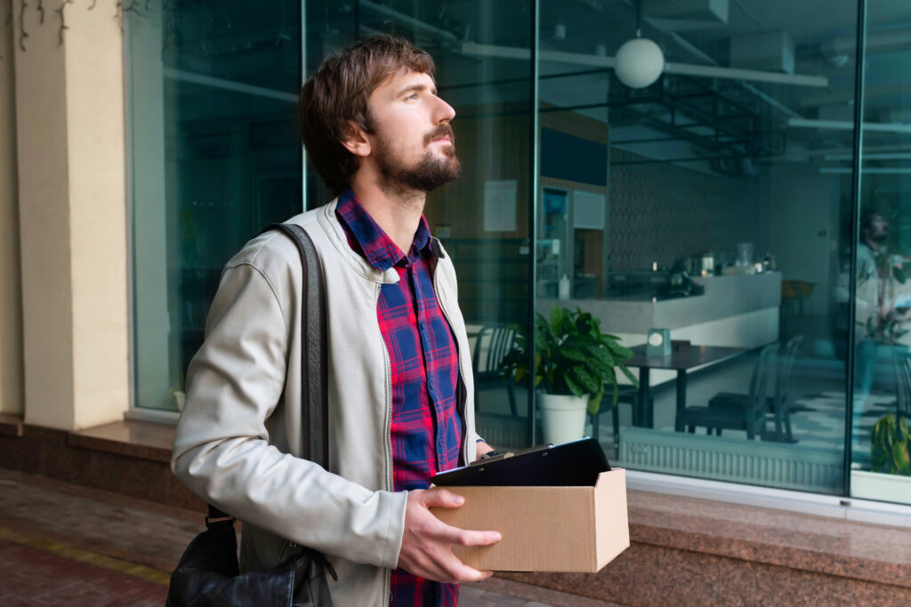 employee offboarding as a man carries out his box after being fired from his job